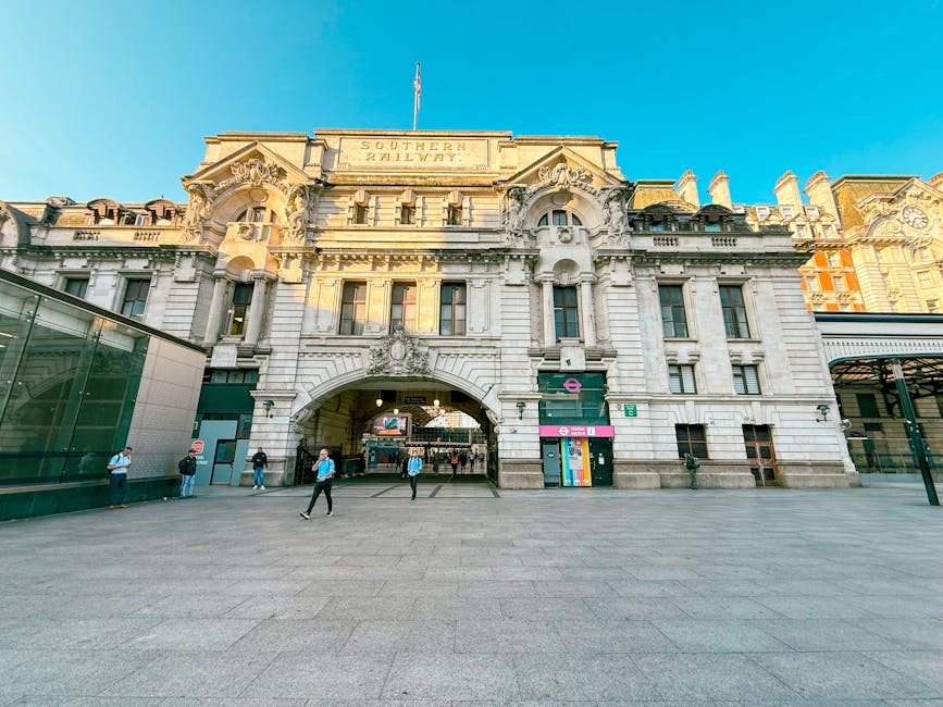 External view of the historic Southern Railway building at Vauxhall Station in Lambeth, London, featuring ornate stone facades, large arched entrance, and decorative architectural details under a clear blue sky. The open plaza in front shows a few pedestrians walking and standing, with modern glass extensions on the sides. Lambeth Cleaners provides domestic cleaning services near this area, offering surface cleaning, deep cleaning, and sanitisation for residential and commercial premises.